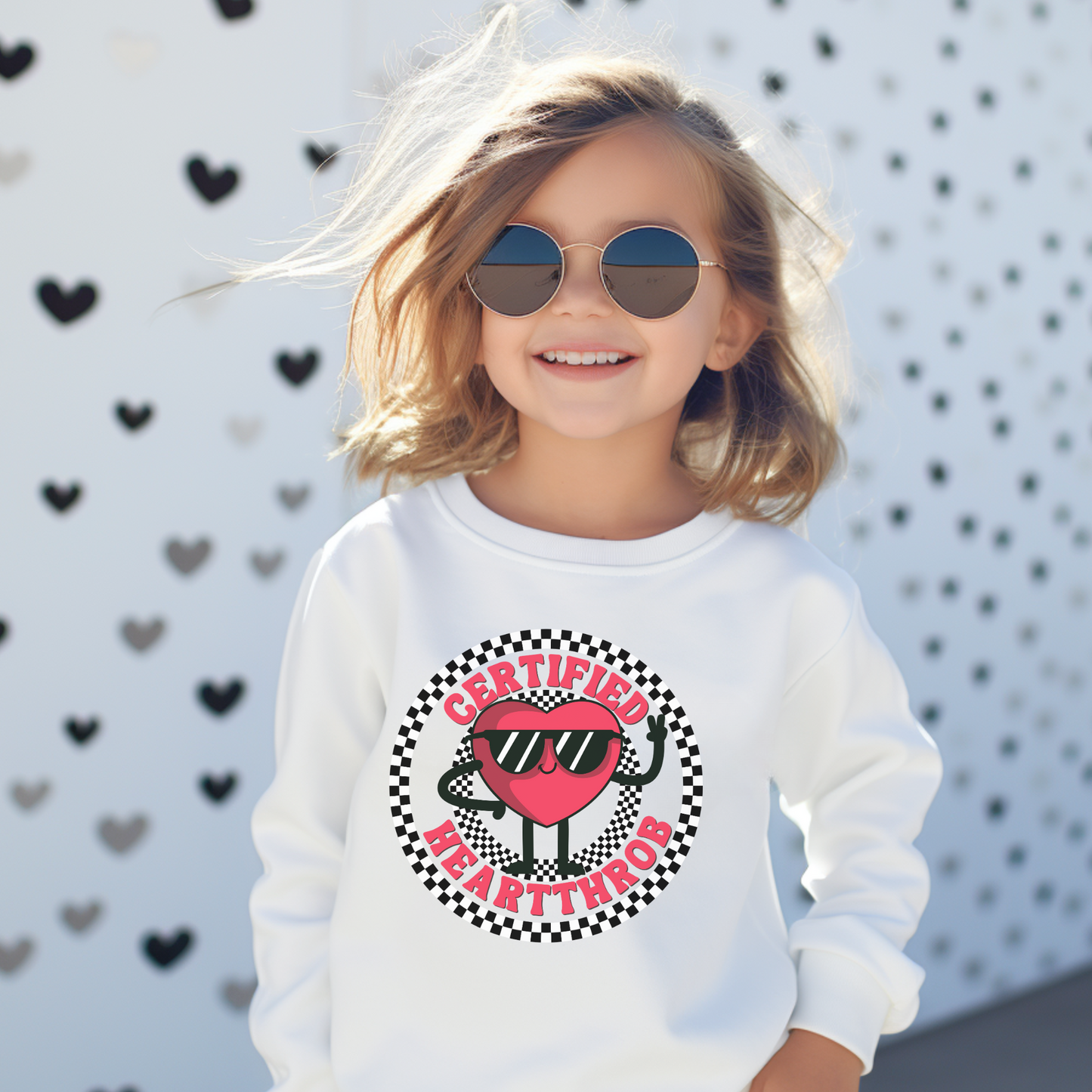 Image: Certified Heartthrob Sweatshirt for kids. This Valentines Day sweater for boys or girls is available in white or gray. It features a checker pattern ring, with a cartoon heart man wearing sunglasses, with the text Certified Heartthrob, by jaecrece