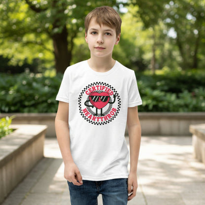 A child models a white youth graphic tee decorated with a playful Certified Heartthrob Valentine's Day design. A cartoon heart character wearing sunglasses sits inside a bold black and white checkerboard circle, with the phrase Certified Heartthrob surrounding the illustration. The fun design brings a cheerful personality to a child's holiday outfit.