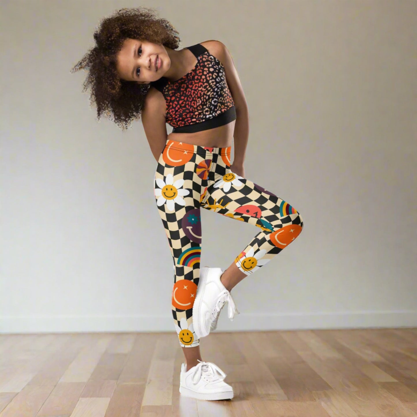 Checkerboard Girls Leggings in sizes 2T–7 showcase a beige and black wavy pattern with playful smiley faces, rainbows, and daisies. These fun toddler leggings are made from a soft and stretchy polyester-spandex blend, designed to keep kids comfortable at school, on playdates, or at home. With matching leggings available in youth and women’s sizes, they’re a cute family outfit choice for photos or coordinated gifts.