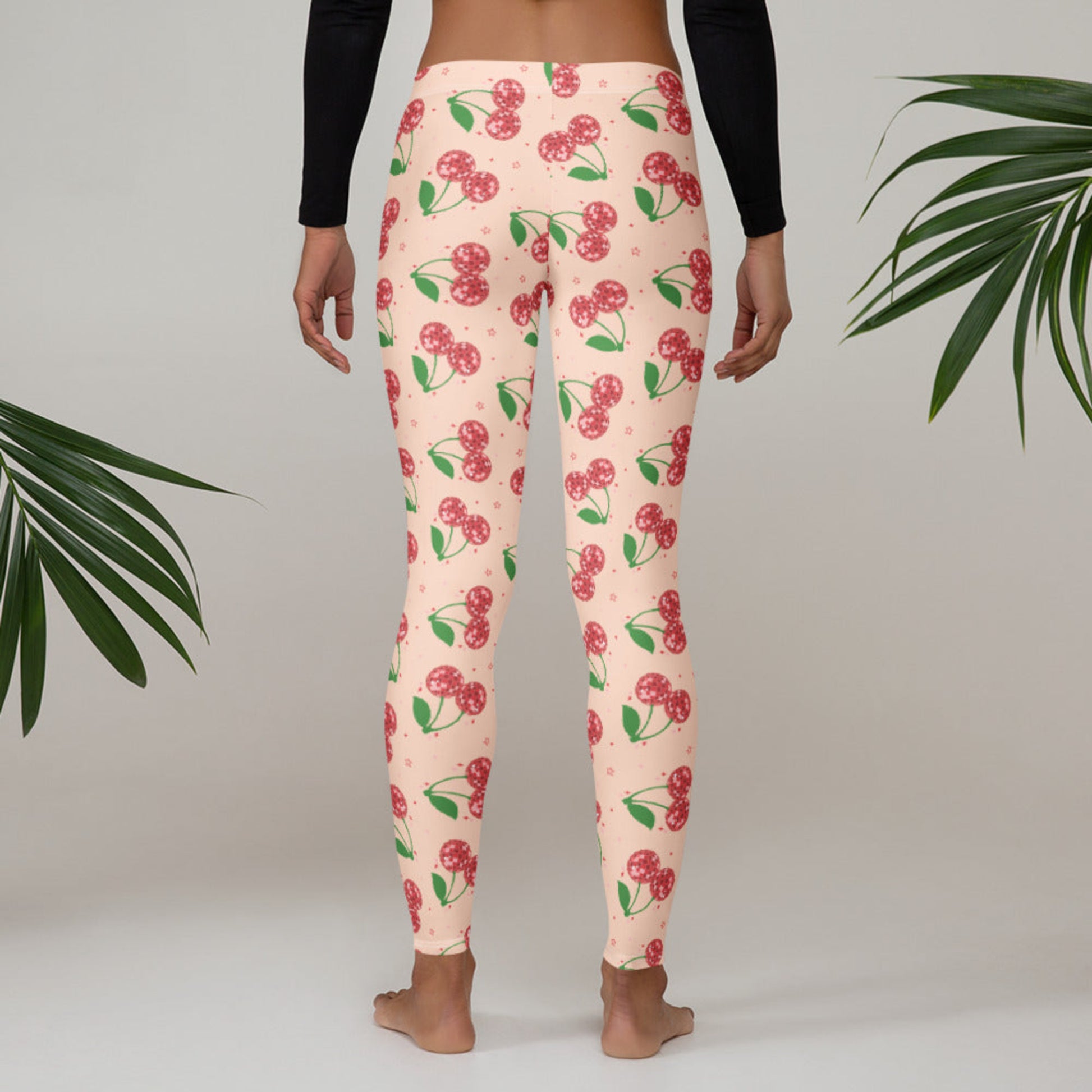 Women’s full length disco cherry leggings featuring a retro cherry aesthetic with disco ball cherry design on a pink background, mid rise leggings made for casual wear, playful fashion, athleisure outfits, travel looks, lounge wear, and women who love bold statement clothing