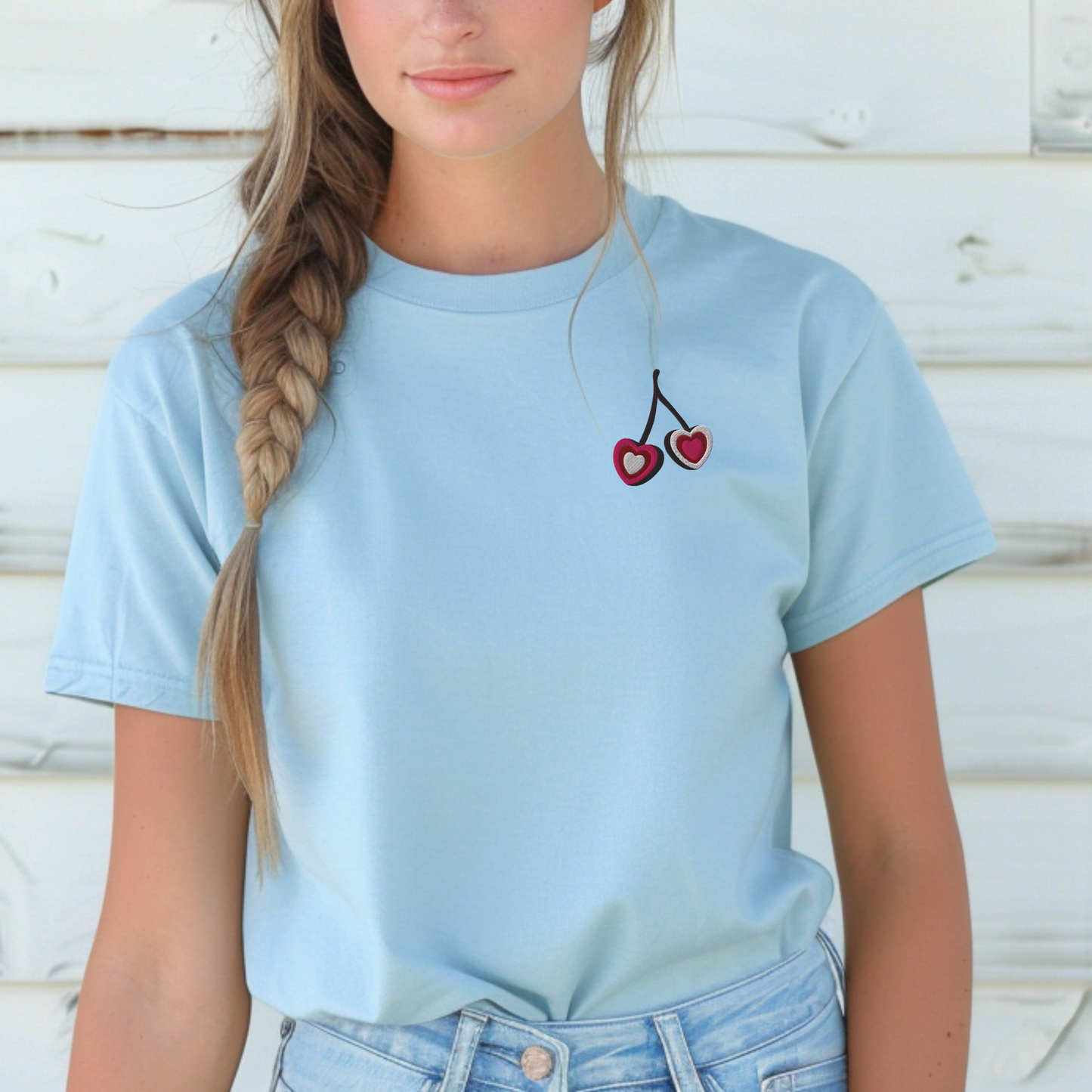 Woman wearing light blue embroidered cherry hearts t shirt featuring subtle red cherry heart embroidery on the front. This relaxed fit Gildan S5000 tee is perfect for casual everyday outfits, errands, and travel days. Soft pastel tone adds a calm aesthetic feel. Matching girls shirt available separately for mommy and me outfits for coordinated family fashion moments.