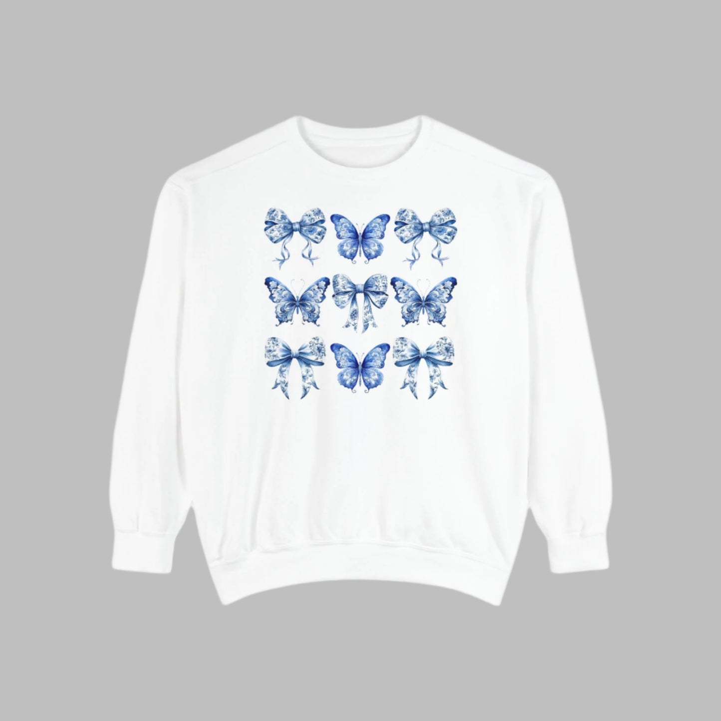 Image: A cozy and cute pullover sweatshirt featuring a nostalgic blue toile pattern with butterfly and ribbon illustrations. Designed for women in sizes XS to XL, this sweatshirt brings elegance to everyday comfort. Match it with your little one in our toddler and youth pieces to create adorable family memories and coordinated style, by jaecrece.