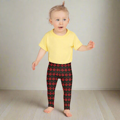 Christmas leggings for girls featuring a classic red and green poinsettia design on black with a repeating Fair Isle inspired pattern. Full length leggings with a high rise waist, available in sizes 2T–20 and perfect for matching family outfits, holiday parties and Christmas pictures.