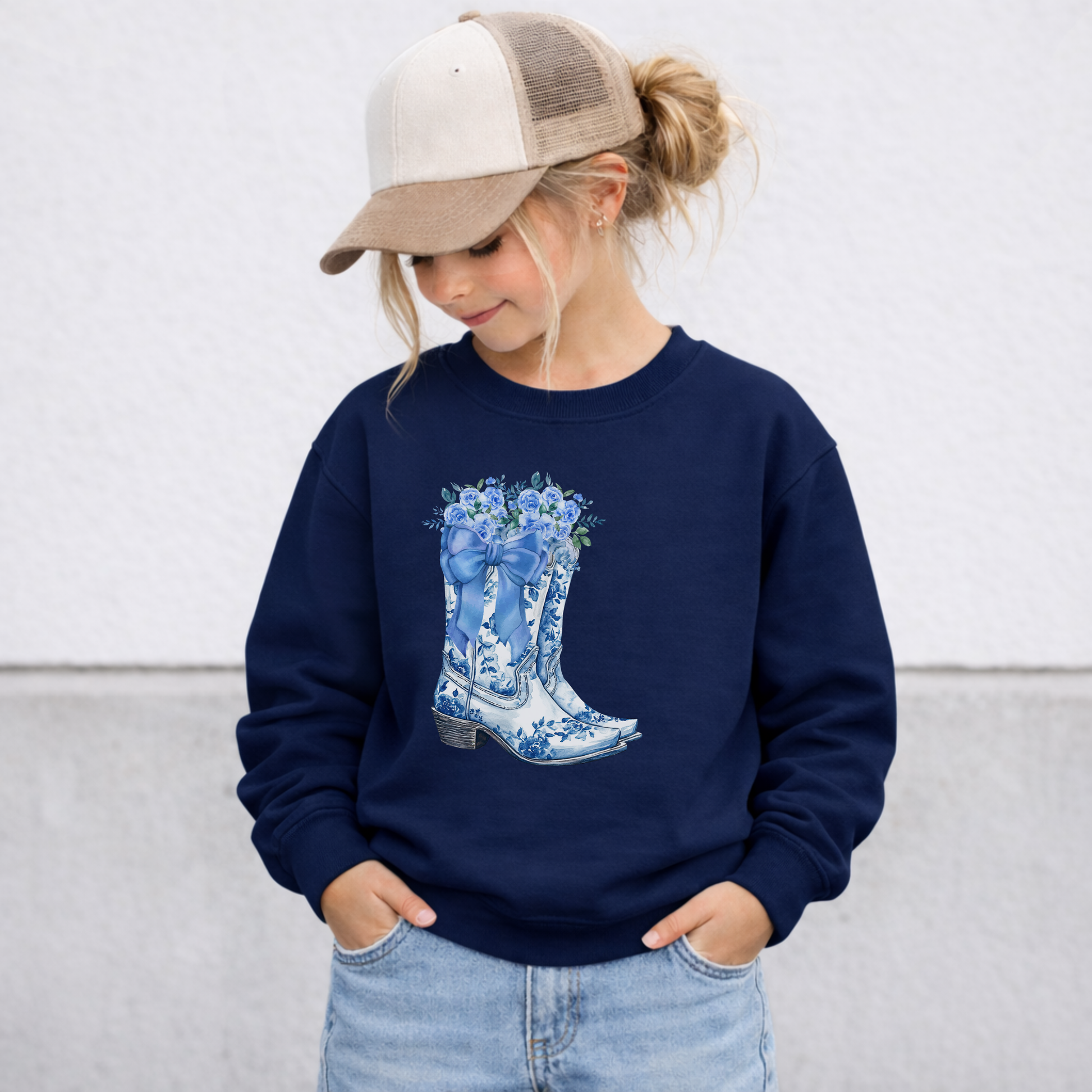 Navy girls sweatshirt with a blue and white toile boots design featuring floral cowboy boots and botanical accents. This cozy crewneck pullover is designed for girls who love Western fashion, country inspired clothing, feminine details and unique graphic sweatshirts for everyday wear.