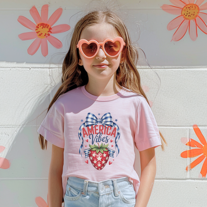 Comfort Colors girls patriotic strawberry shirt celebrating America 250 and the 250th anniversary of the United States with hand drawn strawberry artwork gingham bow details and patriotic stars. Soft garment dyed cotton youth tee in chambray and blossom colors ideal for 4th of July outfits mommy and me matching family looks patriotic parades and Americana inspired summer fashion
