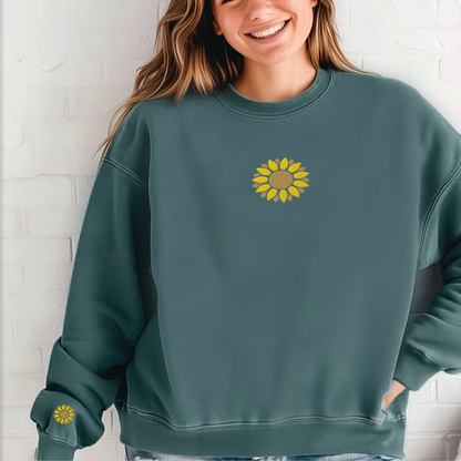 Comfort Colors sunflower embroidered sweatshirt shown in Pepper with detailed sunflower embroidery on the center chest and matching sunflower embroidery on the right wrist. This cozy floral crewneck features a relaxed fit and garment dyed finish for a soft lived in feel. Perfect for gardeners, flower lovers, teachers, moms, and anyone who enjoys nature inspired clothing. Comfortable for everyday wear, casual outings, fall layering, and year round style.