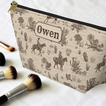Personalized Western accessory pouch featuring a sepia brown cowboy toile design on a warm cream background. The vintage pattern includes horseback riders, cacti, horses and desert plants. This structured travel pouch works as a Western toiletry bag, grooming organizer, cosmetic bag or everyday accessory case.