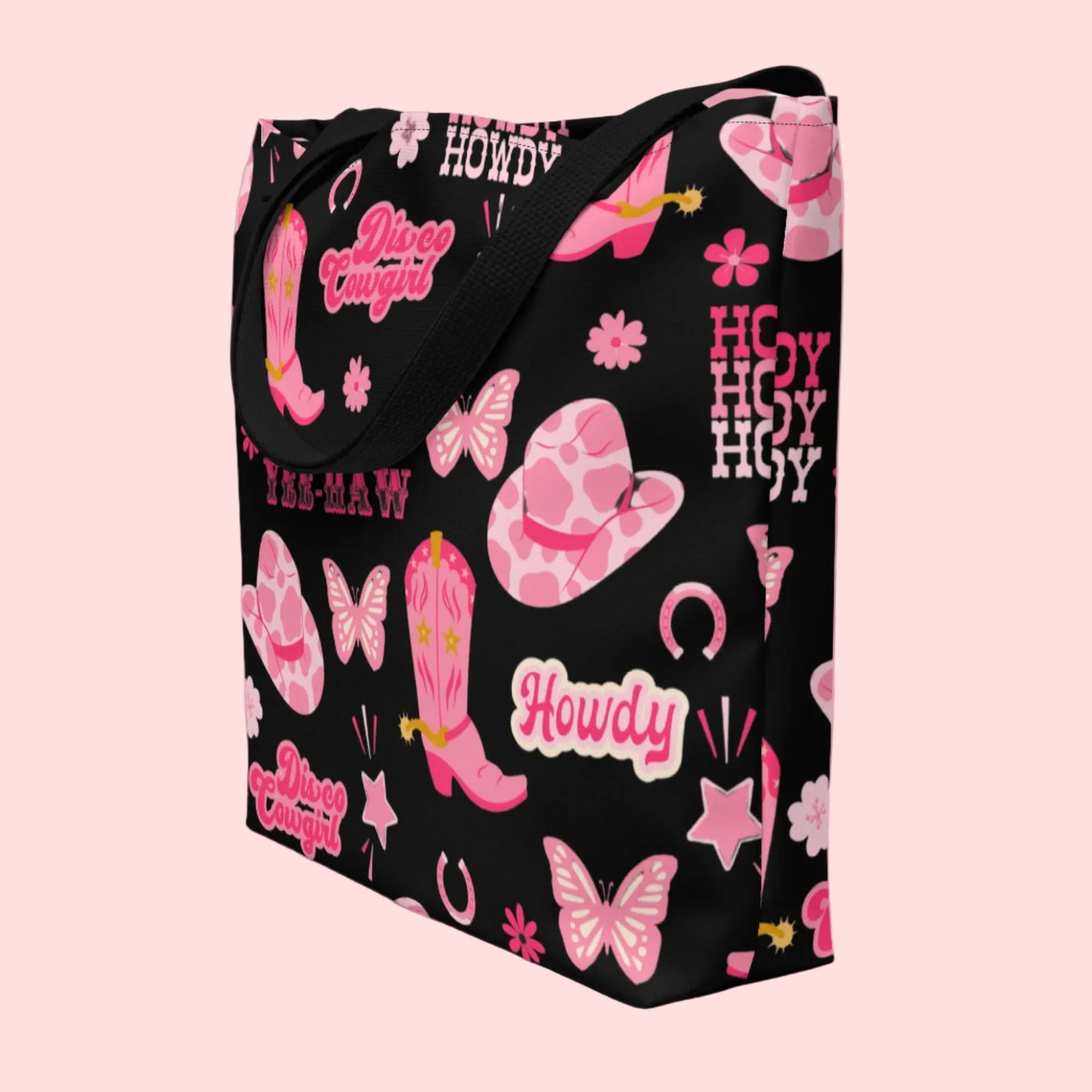 Image: Disco Cowgirl Tote Bag. This western glam canvas shoulder bag has a black background with a pink, white and pink pattern of butterflies, daisies, cowgirl hats and boots. The text on the bag reads Howdy, Yee-Haw and Disco Cowgirl. Great for weekend girls trips or bachelorette parties in Nashville, by jaecrece