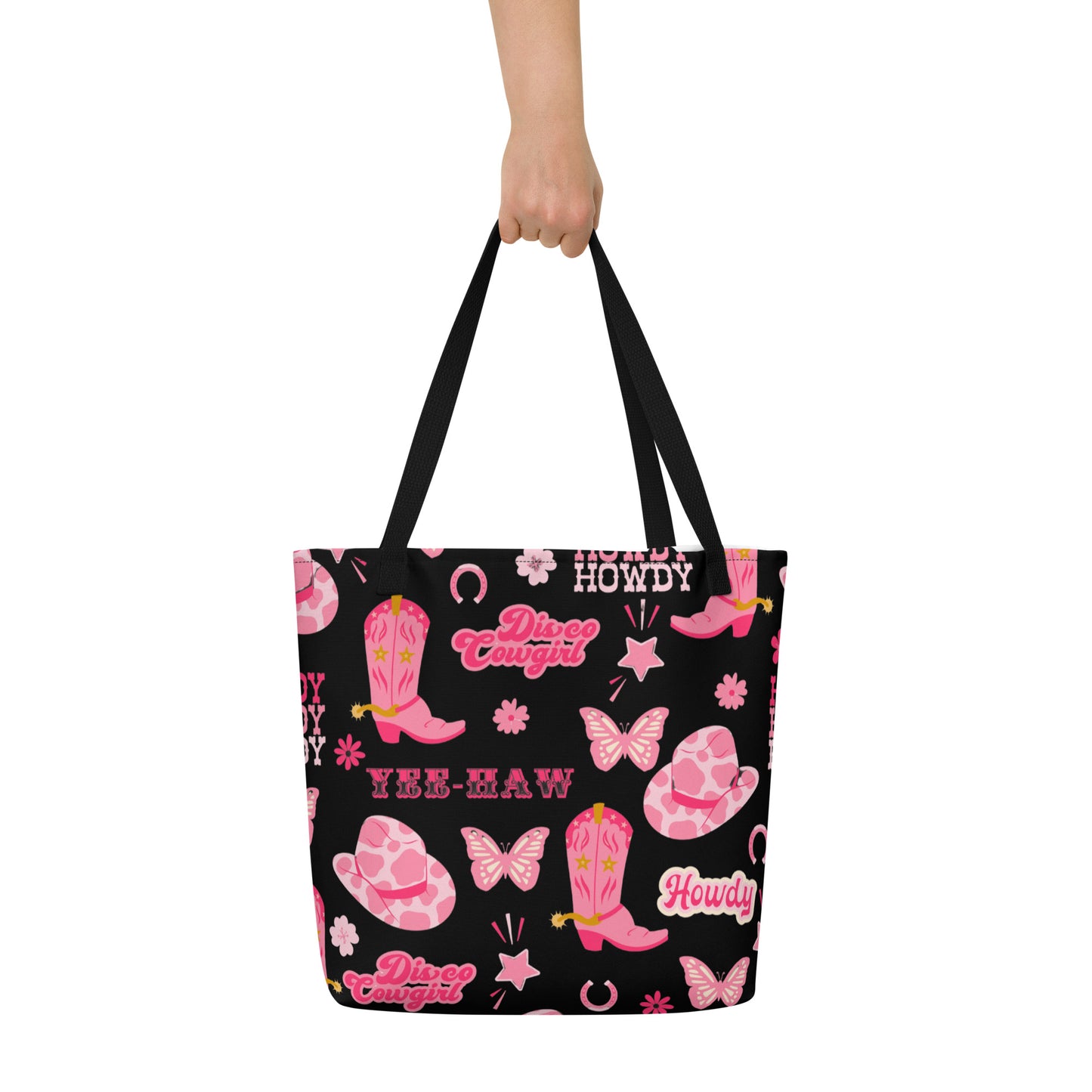 Image: Disco Cowgirl Tote Bag. This western glam canvas shoulder bag has a black background with a pink, white and pink pattern of butterflies, daisies, cowgirl hats and boots. The text on the bag reads Howdy, Yee-Haw and Disco Cowgirl. Great for weekend girls trips or bachelorette parties in Nashville, by jaecrece