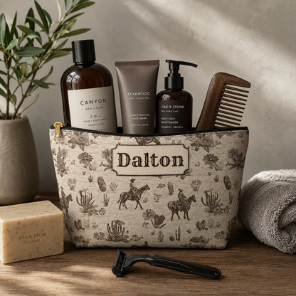Custom Western toile travel pouch featuring a detailed brown and cream cowboy pattern with horses, horseback riders, cacti and vintage ranch inspired illustrations. The personalized accessory pouch has a structured T bottom and zipper closure, making it useful as a toiletry bag, grooming kit or travel organizer.