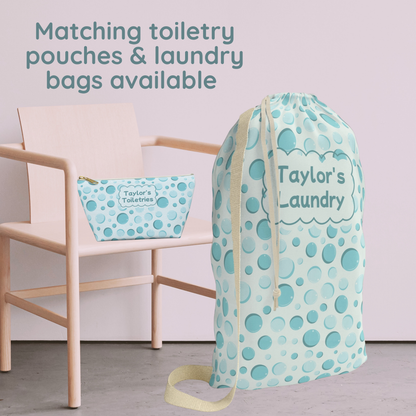 Matching aqua bubble print drawstring laundry bag and personalized kids toiletry pouch featuring a colorful bubble pattern on a light blue background. The laundry bag has cream drawstrings, while the coordinating zippered pouch features a scalloped name label and gold zipper pull. This matching set is perfect for kids, tweens, and teens heading to summer camp, sleepovers, dorm life, and family travel.