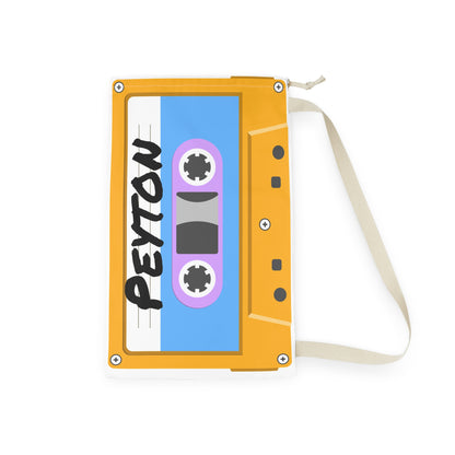 Custom orange laundry sack decorated with a vibrant cassette tape print and personalized name. The roomy 18 x 29 inch bag includes a secure drawstring top and sturdy shoulder strap for carrying clothes between bedroom, dorm room, camp cabin, or laundromat. Bright retro graphics create a fun nostalgic look while the lightweight fabric maintains its shape. Perfect for keeping dirty laundry organized and easy to transport.