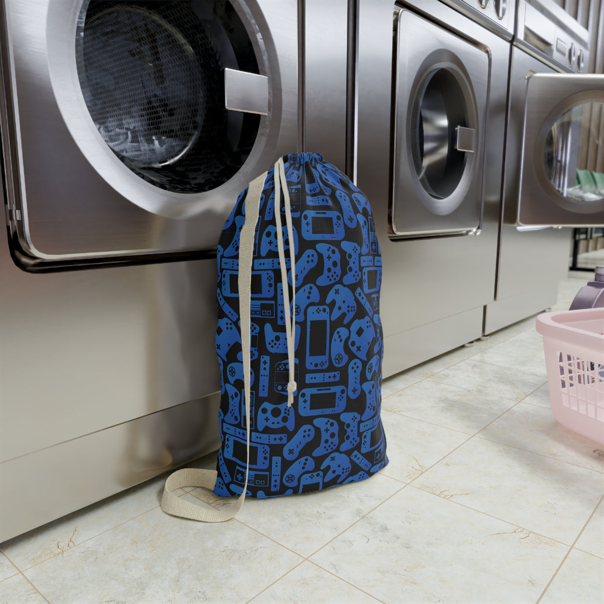 Custom blue gamer laundry bag with black video game controllers and gaming system shapes scattered across the design. Personalized with a name, this reusable clothes bag helps keep dirty laundry together at camp, school, sleepovers, college, or while traveling and makes a fun gift for kids who love gaming.