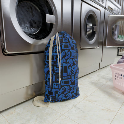 Custom blue gamer laundry bag with black video game controllers and gaming system shapes scattered across the design. Personalized with a name, this reusable clothes bag helps keep dirty laundry together at camp, school, sleepovers, college, or while traveling and makes a fun gift for kids who love gaming.