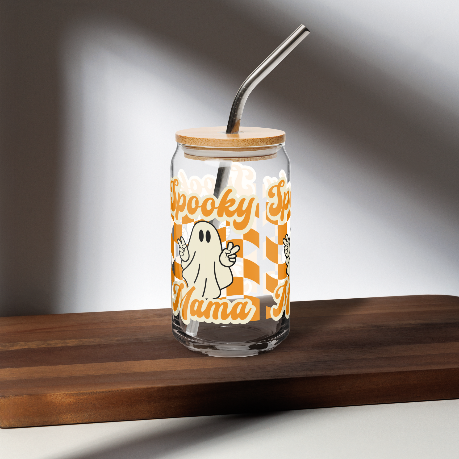 Trendy Spooky Mama tumbler with bamboo lid and metal straw, perfect for iced coffee, tea, or mocktails during fall festivities. Halloween drinkware gift for her with ghost print and orange checkerboard design. Sustainable glass cup ideal for spooky parties, home bar, or coffee corner decor. Ships free and made to order for eco friendly shoppers.