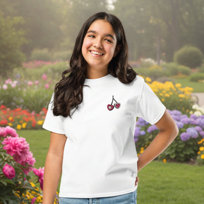 Cute girls cherry tshirt made from breathable cotton with a small embroidered heart cherry detail on the chest. Offered in white, natural, and azalea, this top is perfect for warm weather outfits, school days, and casual family outings. The simple design gives it a soft, feminine feel that fits right into a coquette inspired wardrobe while still being practical for everyday wear and easy styling.