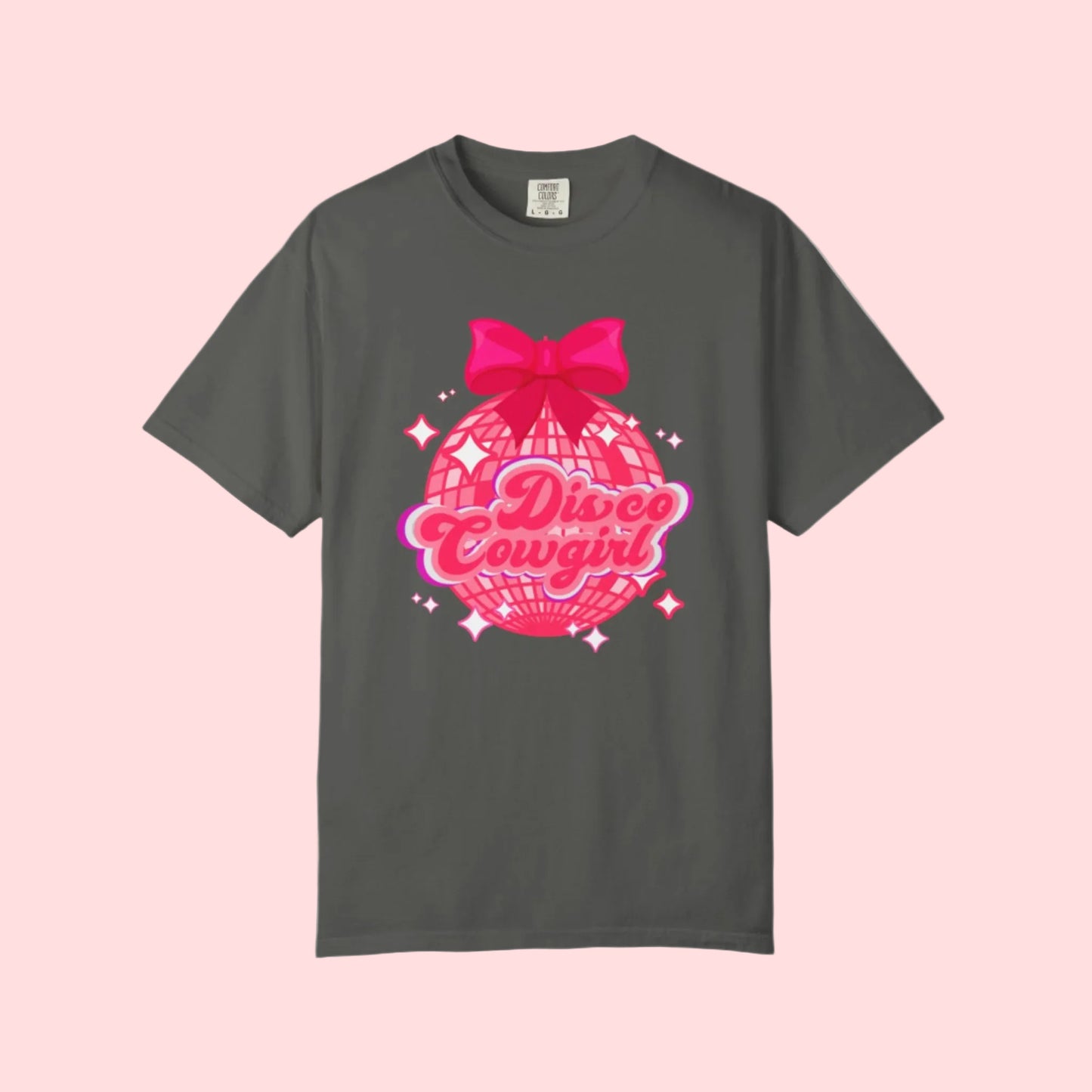 Disco Cowgirl tee for women in Comfort Colors is designed with a glittery pink disco ball, hot pink bow, and bright lettering. Ideal for matching party outfits, this retro western shirt is a cute coquette option for bachelorettes, rodeos, or girls' weekends. Available in S–4XL in multiple neutral shades for a flattering, oversized fit.