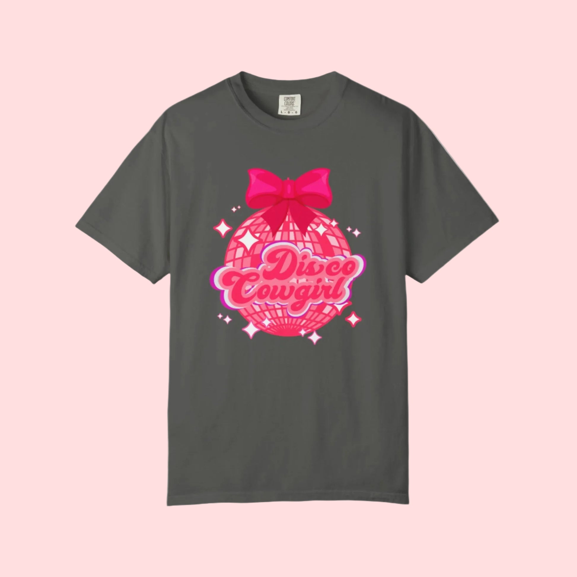 Disco Cowgirl tee for women in Comfort Colors is designed with a glittery pink disco ball, hot pink bow, and bright lettering. Ideal for matching party outfits, this retro western shirt is a cute coquette option for bachelorettes, rodeos, or girls' weekends. Available in S–4XL in multiple neutral shades for a flattering, oversized fit.