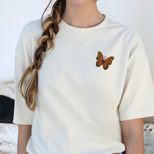 Image: Close-up of a soft Comfort Colors shirt featuring an embroidered monarch butterfly design, ideal for spring fashion lovers and fans of pollinator awareness. This nature-inspired cottagecore shirt is a thoughtful Mother's Day gift or birthday surprise for women who adore botanical prints and subtle wildlife elements in their wardrobe. Perfect for butterfly lovers, nature teachers, or garden enthusiasts, by jaecrece.