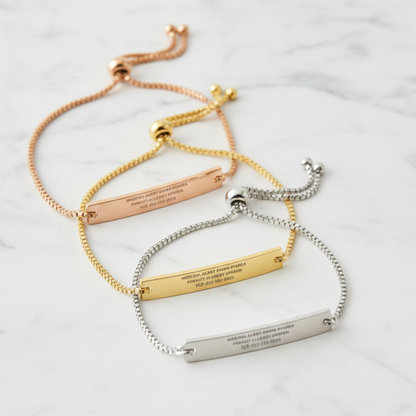 Three adjustable bar bracelets with engraved names, emergency medical information and phone numbers, shown in rose gold, yellow gold, and silver metal finishes on a light cream background.