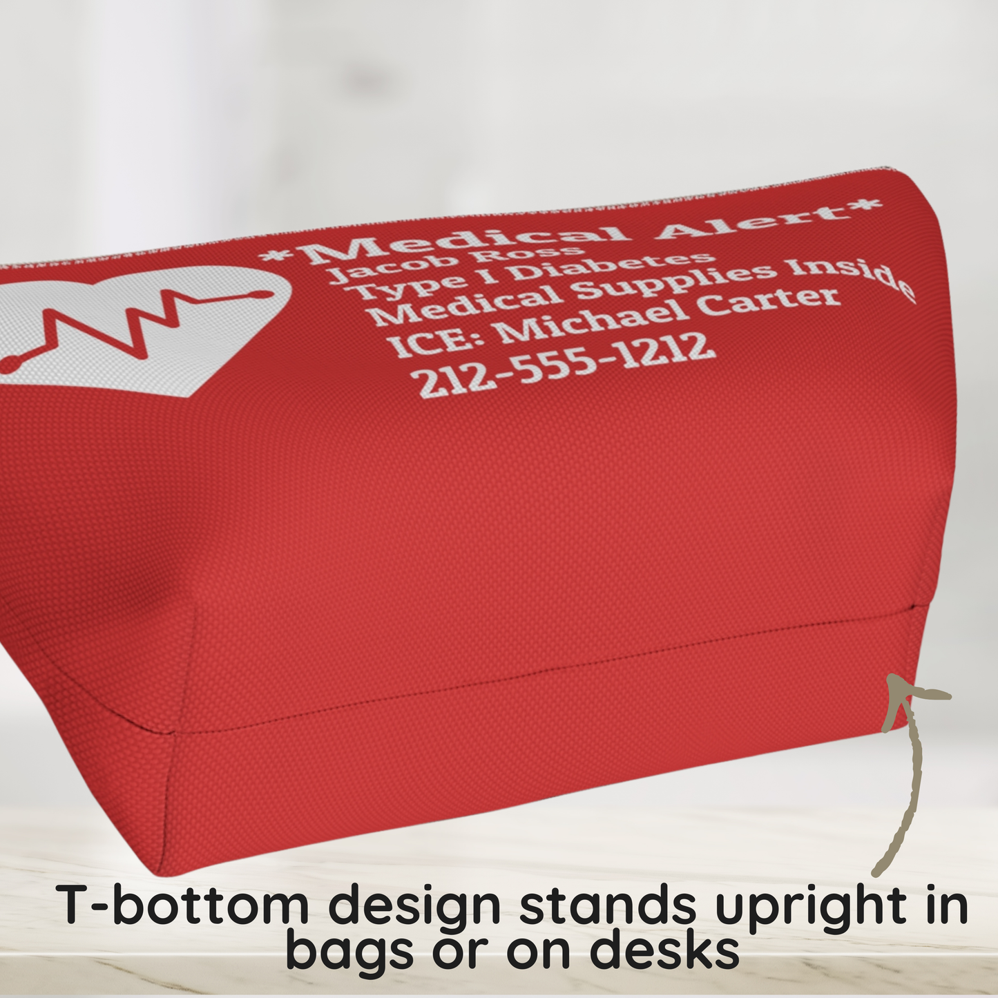 A red medical alert pouch with white printed text and a white heart monitor graphic, shown on a light background with a text overlay at the bottom explaining its T-bottom design. T bottom design of a medical alert pouch showing the structured base that helps the pouch stand upright.
