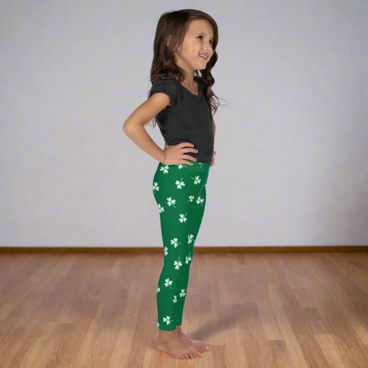 Girls St. Patrick's Day shamrock leggings featuring a bright green background with white four leaf clover print, high rise waistband, and comfortable full length fit for kids.