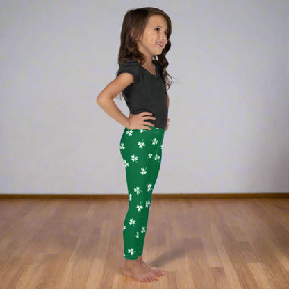 Girls St. Patrick's Day shamrock leggings featuring a bright green background with white four leaf clover print, high rise waistband, and comfortable full length fit for kids.