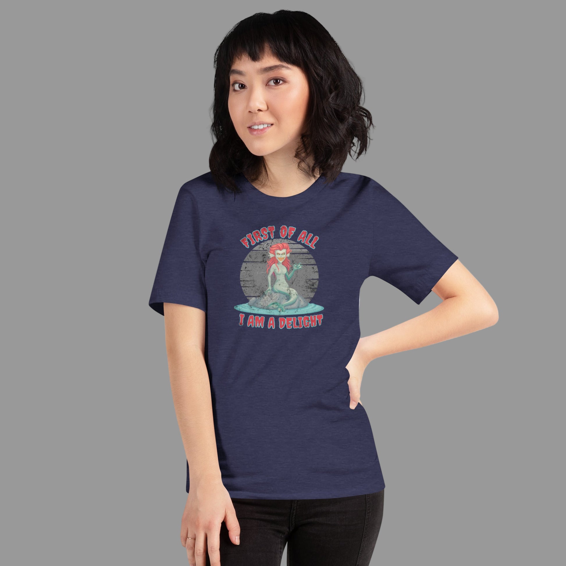 Gothic mermaid graphic t-shirt featuring ‘First of All I Am a Delight,’ perfect for sarcastic ocean humor, mythology lovers, Ren Faire costumes, and Halloween events, unisex Bella Canvas 3001 shirt in Black, Heather Midnight Navy, Heather Grey, XS–5XL.