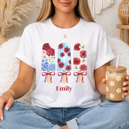 Women's patriotic floral popsicle T shirt with red white and blue flowers and ribbon bows, a cute Americana shirt for Fourth of July celebrations and summer parties