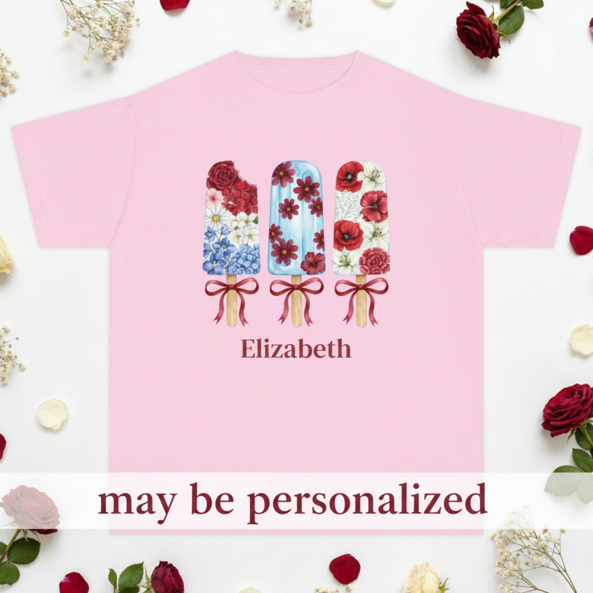 A light pink short sleeve t-shirt with a graphic of three floral popsicles and the name 'Elizabeth' printed below it, shown on a plain white background. The text reads 'may be personalized'. This floral patriotic popsicle tshirt is the perfect family matching tee for 4th of July, Labor Day or Veterans Day.