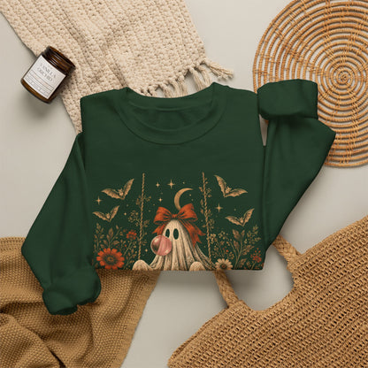 Vintage ghost Halloween sweatshirt showing a ghost relaxing on a swing while blowing a bubble with bubble gum. Surrounding flowers, leaves, bats, lace details, stars and a crescent moon create a whimsical vintage inspired design for autumn and Halloween.