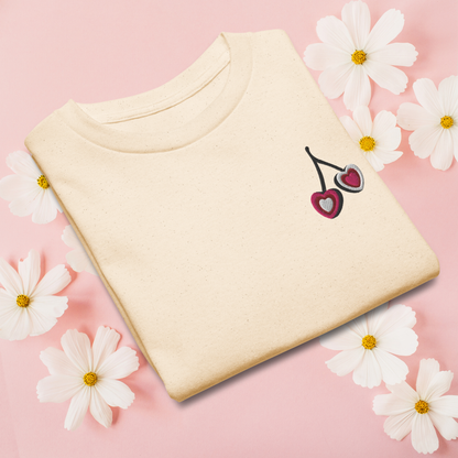 Girls cherry embroidered tshirt in soft cotton, featuring a small heart shaped cherry design on the chest. Available in white, natural, and azalea, this top is ideal for everyday outfits, from school to weekend outings. The minimal design keeps it easy to style, while the embroidery adds a fun, feminine detail that girls will love wearing again and again.