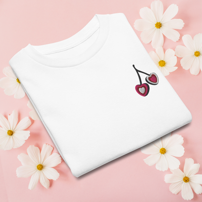 Girls embroidered cherry shirt made from soft, breathable cotton with a small heart shaped cherry detail. Available in white, natural, and azalea, this top is perfect for everyday wear, whether she is heading to school, playing outside, or going out with family. The clean, simple design gives it a timeless feel, while the embroidery adds just enough personality to make it special.