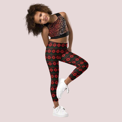 Girls’ Christmas poinsettia leggings in sizes 2T–20 featuring a black background with red poinsettias and green leaves in a repeating Fair Isle inspired pattern. Full length with a high rise waist, these festive leggings are perfect for Christmas outfits, parties and family photos.