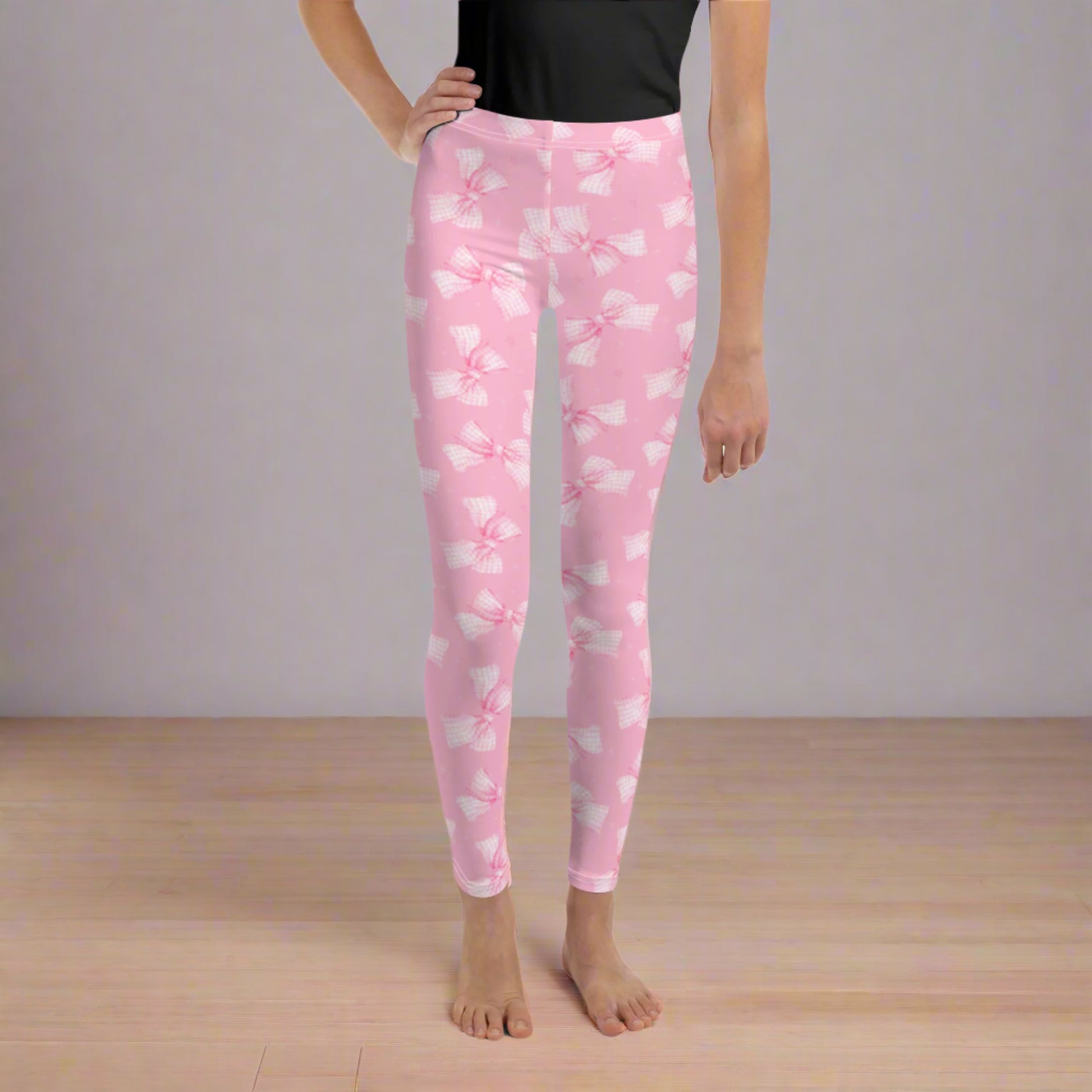 Image: These pink coquette leggings in youth sizes 8 to 20 feature adorable gingham bows scattered across soft, stretchy fabric. Ideal for girls who love all things girly, these leggings are perfect for ballet, weekend fun, or dressing up with friends. Their sweet design makes them a thoughtful gift for tweens and teens who adore unique style, by jaecrece.