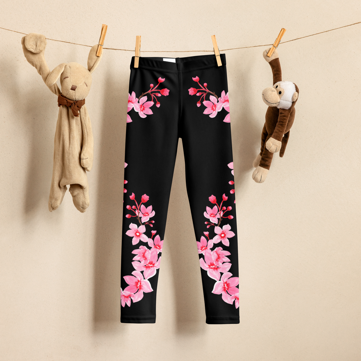 Girls cherry blossom leggings featuring delicate pink sakura flowers and branches flowing down the legs against a black background. These full length kids leggings have a high rise waistband and stretchy fabric designed for comfortable everyday wear, school, playtime, and casual outfits for toddlers and young girls.