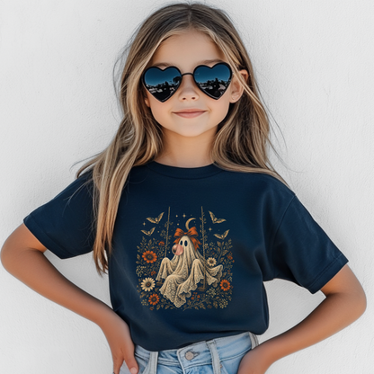 Girl wearing a navy Halloween T shirt featuring a vintage inspired ghost blowing a bubble with bubble gum, surrounded by orange flowers, botanical foliage, bats, stars, lace and a bow. A whimsical girls graphic tee for Halloween parties, fall outfits, pumpkin patches and spooky season fun.
