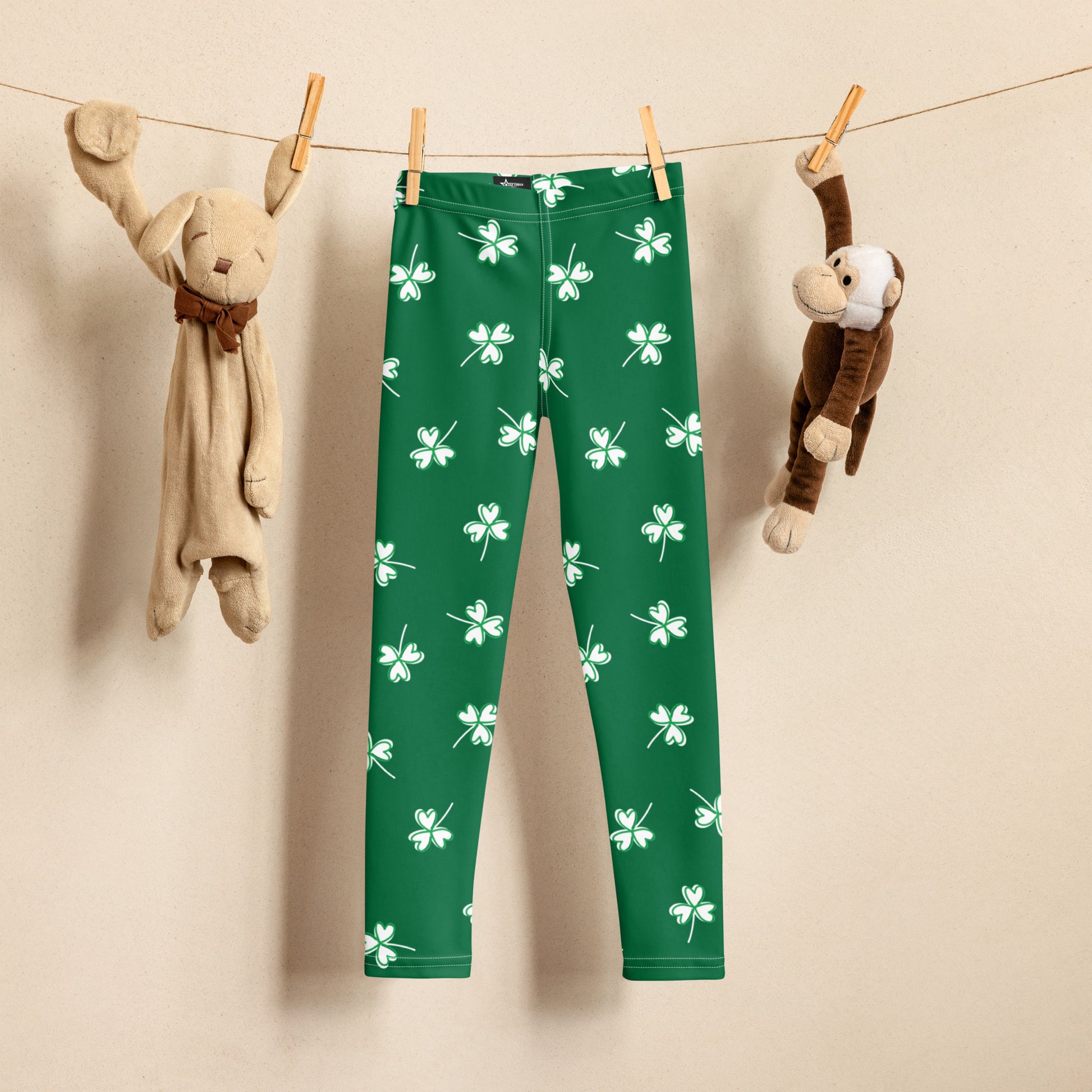 Girls St. Patrick's Day shamrock leggings featuring a bright green background with white four leaf clover print, high rise waistband, and comfortable full length fit for kids.