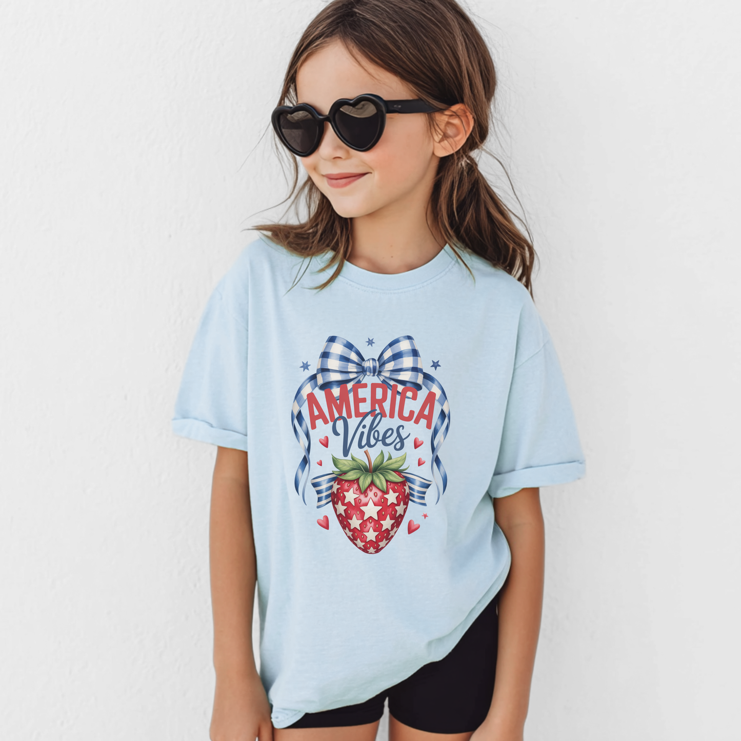 Girls patriotic strawberry Comfort Colors 9018 shirt in chambray featuring vintage Americana artwork with strawberry graphic gingham bow patriotic stars and heart accents. Soft garment dyed cotton youth tee with relaxed fit perfect for America 250 celebrations 4th of July outfits mommy and me matching looks patriotic family photos Memorial Day summer vacations and red white and blue holiday style for girls