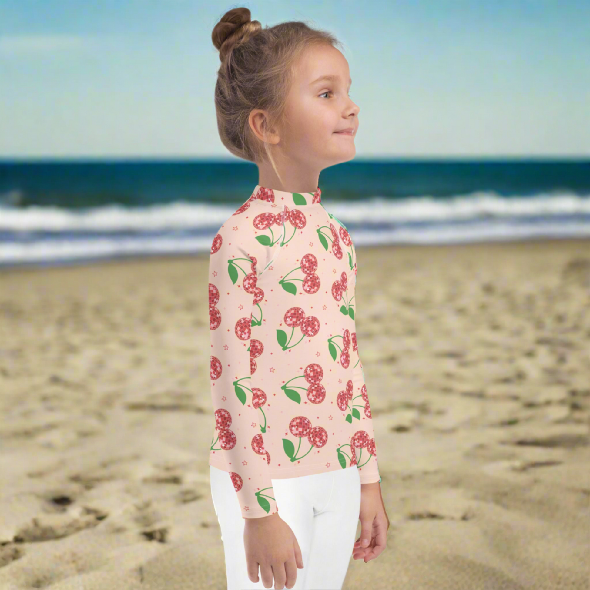 Girls pink cherry rash guard with long sleeves and a fitted design, made for toddlers sizes 2T to 7. Features a vibrant disco cherry pattern and provides UPF 50 sun protection for safe outdoor play. This swim top is perfect for beach vacations, pool days, and summer activities. Soft stretch fabric ensures comfort and flexibility. Part of a matching mommy and me swim collection for fun and coordinated family style.