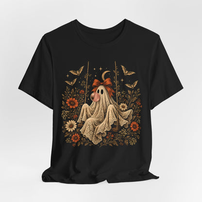 Gothic cottagecore inspired Halloween shirt featuring a vintage ghost sitting on a swing while blowing bubble gum. Floral and botanical details surround the ghost along with bats, lace, stars and a crescent moon for a romantic whimsical spooky season look.