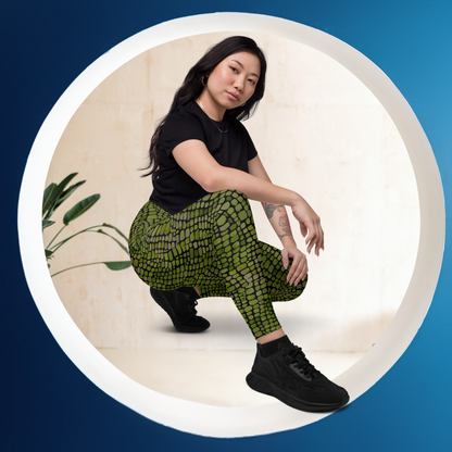 Person wearing green reptile scale patterned yoga pants and black shoes on a blue background