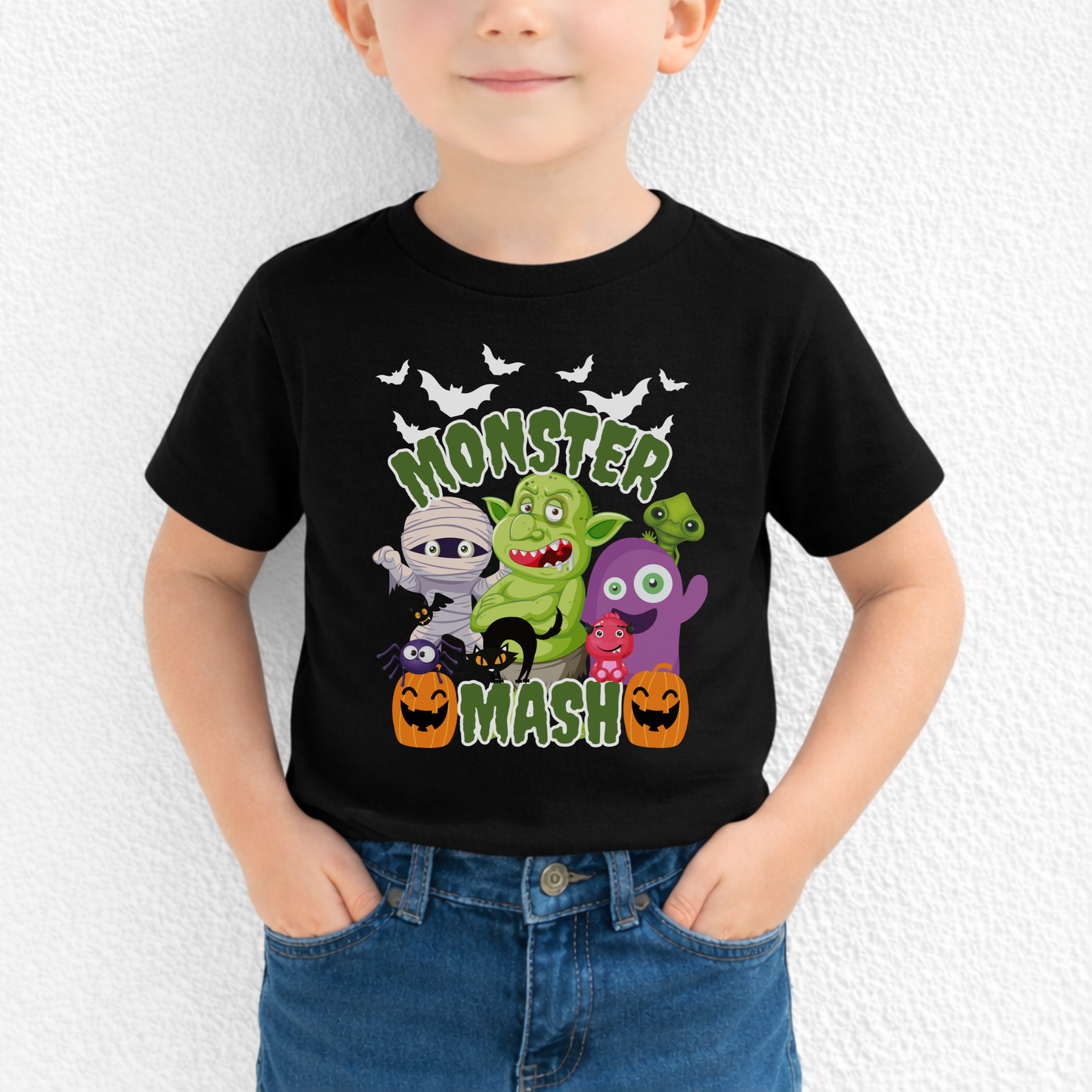 Halloween Monster Mash graphic t shirt featuring fun cartoon style spooky characters including ghost, mummy, zombie, troll, black cat, bats, and pumpkins printed on a black Bella Canvas tee. The design has bold green slime Monster Mash text, making it a festive Halloween shirt for kids and adults, perfect for fall outfits, school parties, trick or treat night, and family matching Halloween looks.