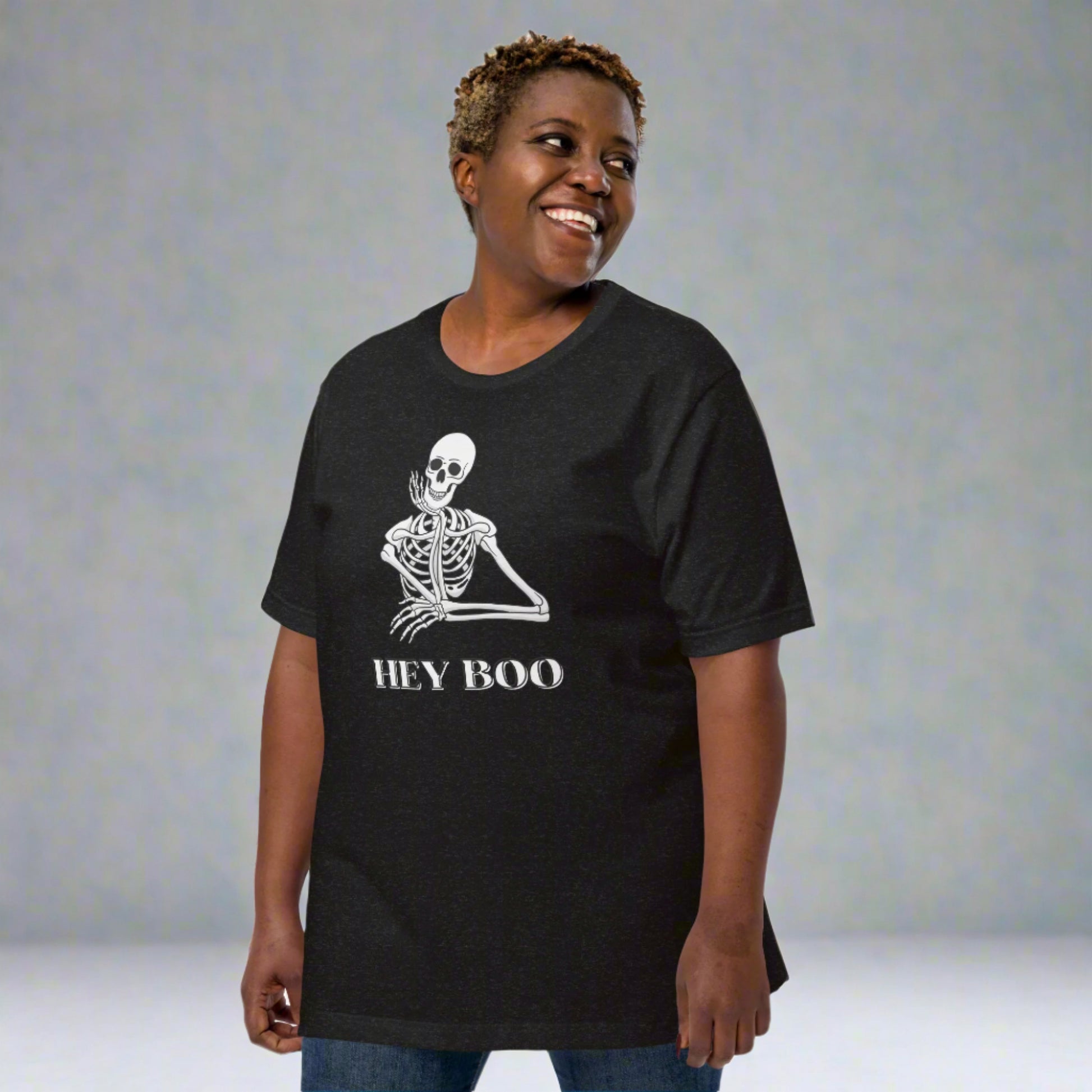 Unisex Hey Boo Skeleton Halloween Shirt for spooky season, printed on Bella Canvas 3001 Black Heather in sizes XS–5XL. Featuring a cheeky skeleton design with the words “Hey Boo,” this funny Halloween graphic tee is perfect for men and women who love playful fall fashion. Lightweight, soft, and pre-shrunk, it’s a go-to Halloween party shirt, trick-or-treat tee, or everyday fall wardrobe staple for celebrating the season with humor and style.