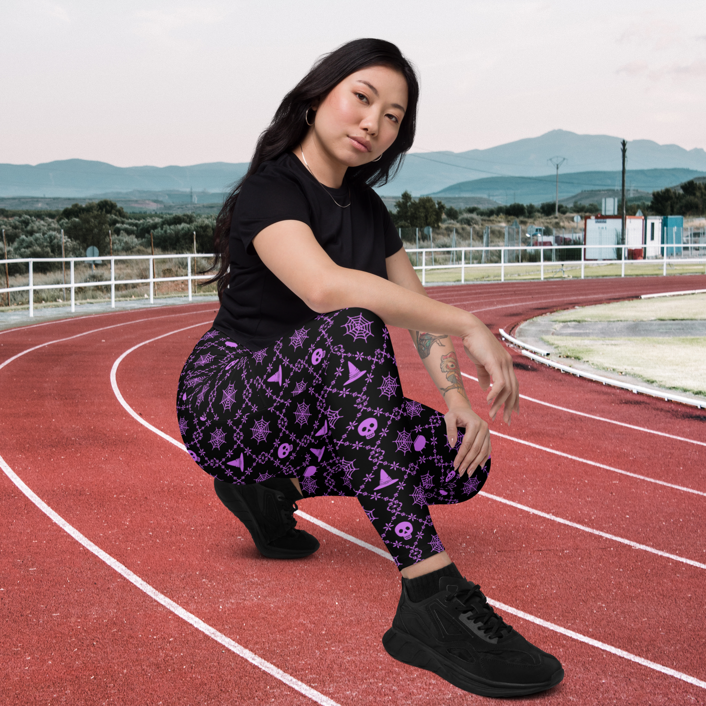 Women's spooky season leggings with pockets featuring a purple and black geometric Halloween pattern, full length design, high waist and compression fit, available in inclusive sizes 2XS through 6XL, perfect for Halloween outfits, trick or treating, cozy fall days, parties and family celebrations