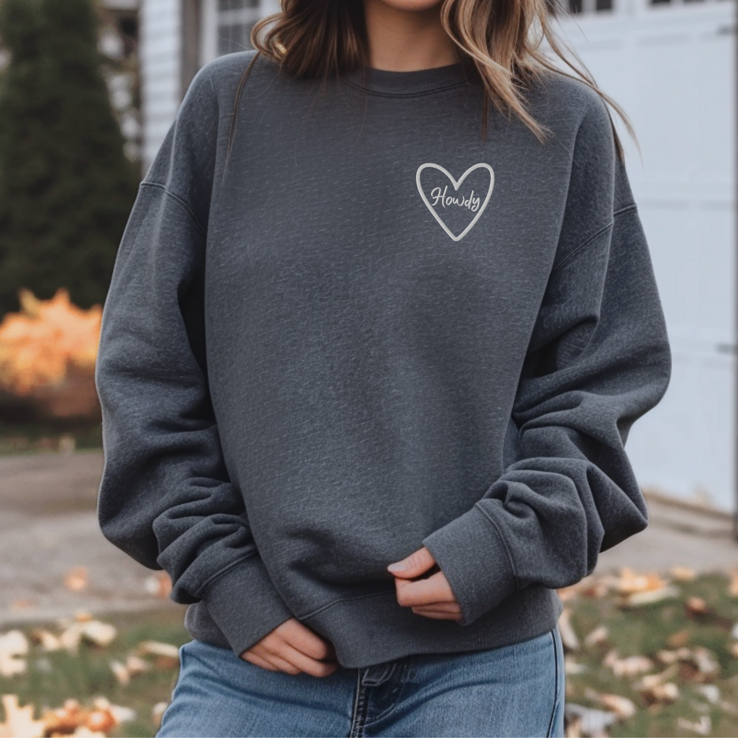 Embroidered Howdy sweatshirt made on Gildan 18000 heavy blend crewneck featuring cozy relaxed fit and soft fleece interior. Western inspired game day sweatshirt perfect for Texas college football, tailgates, and stadium events. Unisex design ideal for layering during fall sports season. Available in multiple colors including maroon, black, forest green, heliconia, and dark heather. Stylish casual outfit for students, fans, and alumni.