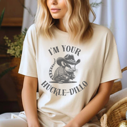 Image: A funny and stylish armadillo T-shirt featuring a detailed dark grey illustration of an armadillo wearing a sheriff’s outfit. The armadillo sports a cowboy hat with a small Texas emblem, giving it a distinct western feel. Perfect for country music lovers, Texas souvenir collectors, or animal enthusiasts who enjoy unique fashion. This comfortable unisex tee makes a great birthday or holiday gift for armadillo fans, by jaecrece.
