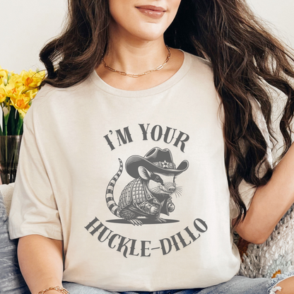 Image: A country-style T-shirt featuring a cartoon armadillo dressed as a Texas sheriff, wearing a cowboy hat with a small Texas emblem on the brim. This quirky and humorous design is a must-have for animal lovers, desert wildlife enthusiasts, and fans of western fashion. Ideal as a Texas souvenir or a fun gift for someone who loves cute animal shirts with a country twist. A perfect addition to any casual wardrobe, by jaecrece.