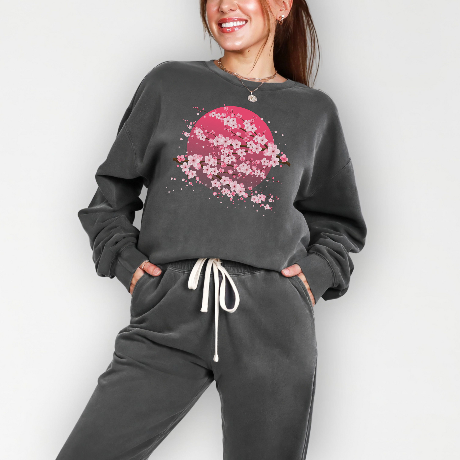 Womens cherry blossom sweatshirt with a soft pink moon and floral sakura branches printed on a Comfort Colors garment dyed pullover, relaxed fit with a cozy feel that works for everyday wear, easy to pair with jeans or joggers for a casual look, lightweight yet warm cotton fabric that feels soft against the skin, nature inspired design with a feminine touch, great gift idea for birthdays, holidays, or anyone who loves floral clothing