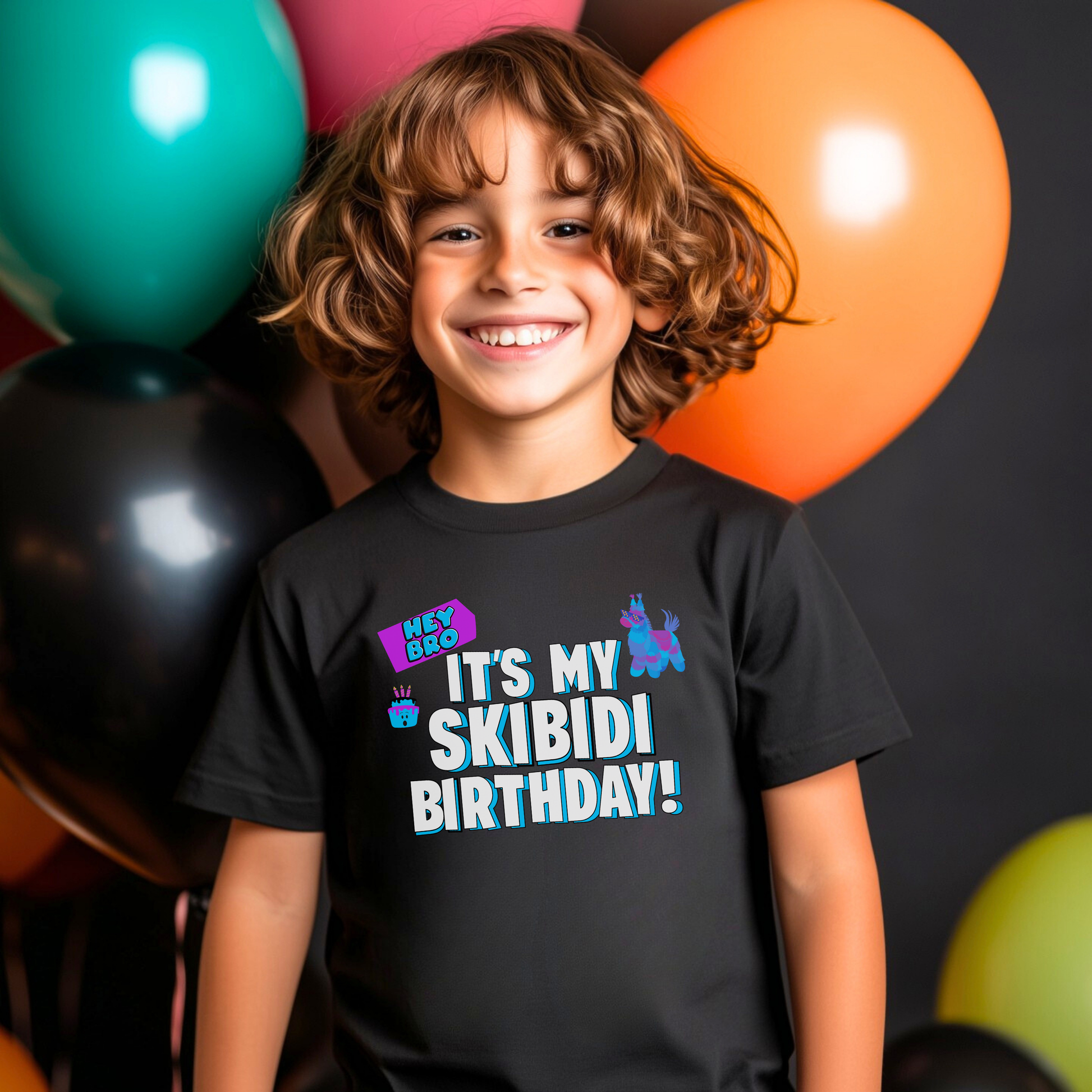 A smiling young boy with curly brown hair stands in front of colorful balloons wearing a black graphic t-shirt that reads 'IT'S MY SKIBIDI BIRTHDAY!' in white and blue letters with a purple party hat graphic. Kids Skibidi birthday shirt featuring a colorful Hey Bro It’s My Skibidi Birthday graphic with bold blue and white lettering on a black Bella Canvas youth tee, perfect for a funny birthday party outfit